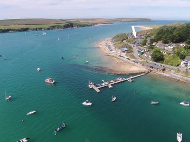 A coastal area with a pier and boats docked near a small beach with buildings and roads at Upper Deck  Rock