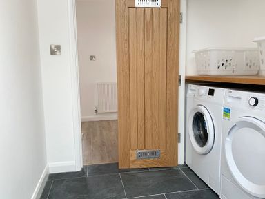 A laundry room with washing machine and dryer under a wooden countertop and a wooden door at Upper Deck in Rock