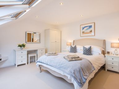 A bedroom with a bed two bedside tables a wardrobe a dressing table and skylight windows at Upper Deck in Rock