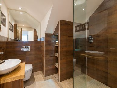 A bathroom with a wooden vanity and sink a toilet built-in shelves and a glass shower enclosure at Upper Deck in Rock
