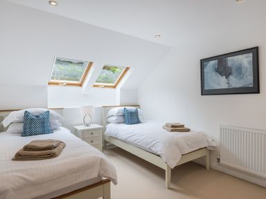 A bedroom with two single beds a nightstand with lamp two skylight windows and a framed picture on the wall at Upper Deck Rock