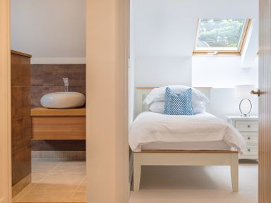 A bedroom with a white bed and blue pillow next to a bathroom with a round sink at Upper Deck in Rock