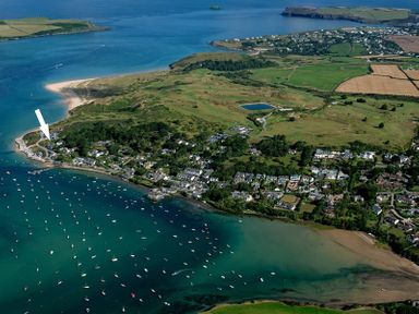 An aerial view of a coastal village with boats in the water and green fields in the background at Upper Deck in Rock