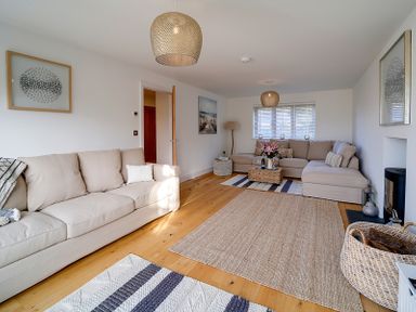 A living room with two beige sofas a wooden floor a rug a coffee table and framed artwork at Elmwood in Port Isaac
