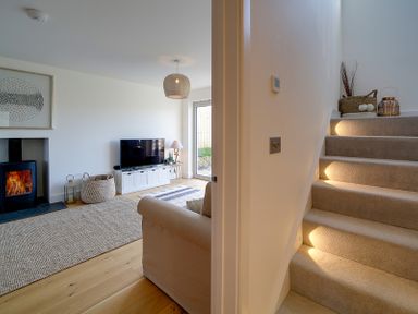 A living room with a fireplace television sofa and stairs with built in lights at Elmwood in Port Isaac