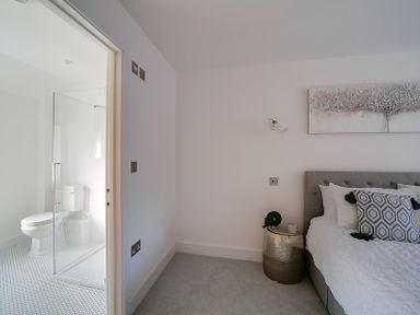 A bedroom with a bed and side table next to an en suite bathroom with a toilet at Elmwood in Port Isaac