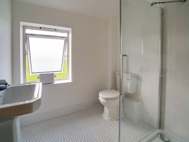 A bathroom with a toilet sink window and a glass shower at Elmwood in Port Isaac