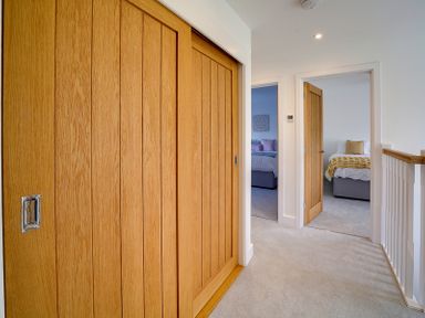 A hallway with wooden sliding doors on the left and two bedrooms visible at Elmwood in Port Isaac