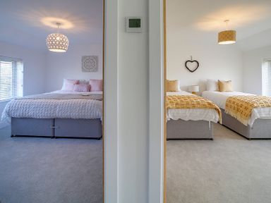 Two bedrooms with beds and wall decorations separated by a white wall at Elmwood in Port Isaac