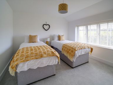 A bedroom with two single beds pillows and blankets near a window at Elmwood in Port Isaac
