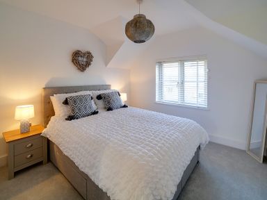 A bedroom with a double bed bedside tables lamps a window with blinds and a standing mirror at Elmwood in Port Isaac