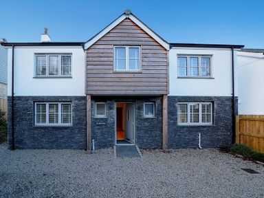 A two-story house with stone and wood exterior and multiple windows at Elmwood in Port Isaac