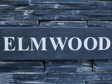 A stone wall with a dark rectangular plaque displaying the word Elmwood