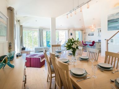 An open dining and living room with a set dining table and chairs at Egloskerry in New Polzeath