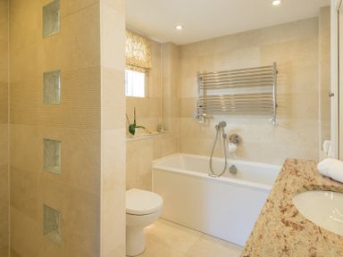 A bathroom with a bathtub toilet sink and towel rack at Egloskerry in New Polzeath