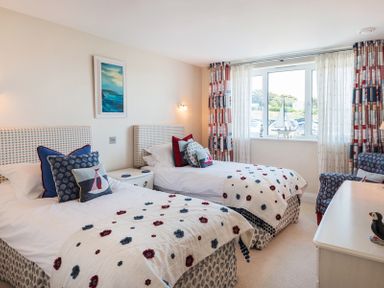 A bedroom with two single beds a chair and a window at Egloskerry in New Polzeath