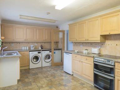 A kitchen with wooden cabinets a washing machine a dryer a dishwasher an oven and a toaster at Greenaway 4 Rockhaven Gardens in Rock