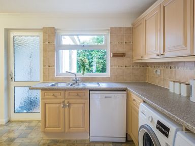 A kitchen with wooden cabinets a double sink a dishwasher a washing machine and a frosted glass door at Greenaway 4 Rockhaven Gardens Rock