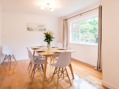 A dining room with a wooden table set with plates glasses and flowers at Greenaway 4 Rockhaven Gardens in Rock