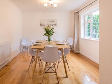 A dining room with a wooden table set with plates and glasses surrounded by white chairs at Greenaway 4 Rockhaven Gardens in Rock
