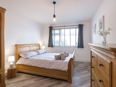 A bedroom with a wooden bed a wooden dresser two bedside lamps and a window at Greenaway 4 Rockhaven Gardens in Rock