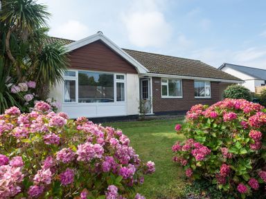 A bungalow with a lawn and pink flowering bushes at Greenaway 4 Rockhaven Gardens in Rock