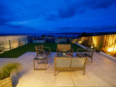 An outdoor patio with chairs and a table overlooking a body of water at Seahaven in Port Isaac