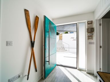 A front door open to a stairway outside with crossed wooden oars mounted on the wall inside at Seahaven in Port Isaac