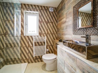 A bathroom with a shower area toilet wall-mounted towel radiator and a rectangular sink at Seahaven in Port Isaac