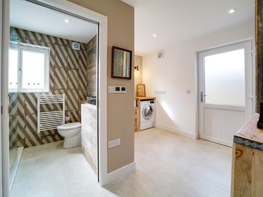A utility room with a washing machine and a bathroom with a toilet and towel radiator at Seahaven Port Isaac