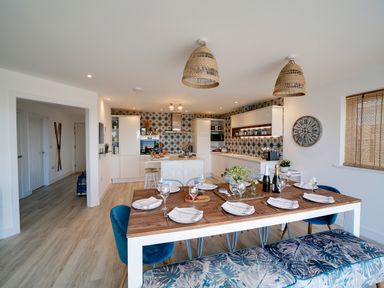 A kitchen and dining area with a wooden table set with plates and glasses at Seahaven in Port Isaac