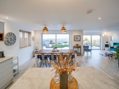 A dining area with a wooden table and chairs and large windows overlooking the sea at Seahaven in Port Isaac