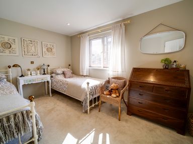 A bedroom with two single beds a white bedside table and a wicker chair with a teddy bear at Seahaven in Port Isaac