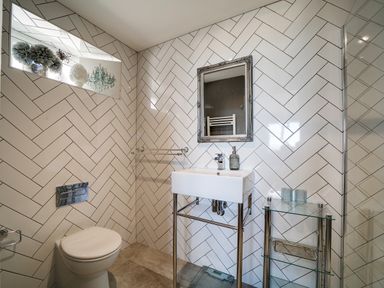 A bathroom with a toilet sink mirror and glass shelves at Seahaven in Port Isaac