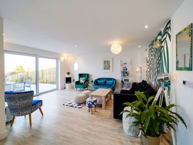 A living room with various chairs a sofa wooden table poufs and a plant at Seahaven in Port Isaac