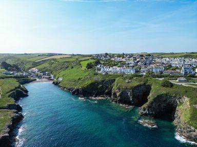 A coastal village with houses on cliffs overlooking a bay with green hills at Seahaven in Port Isaac
