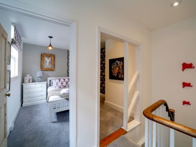 A landing area with a view into a bedroom with a bed and chest of drawers at Grey Roofs in Port Isaac