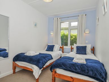 A bedroom with two beds and a window at Hillcroft Bungalow Daymer Bay
