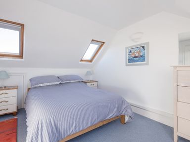 A bedroom with a double bed between two bedside tables and skylight windows at Sea Glimpses in Port Isaac