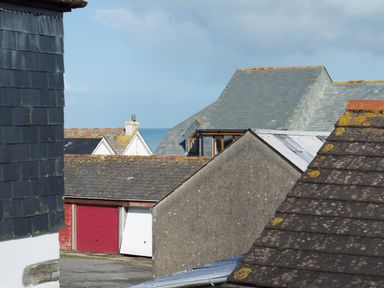A view of rooftops with some garages and a glimpse of the sea at Sea Glimpses in Port Isaac