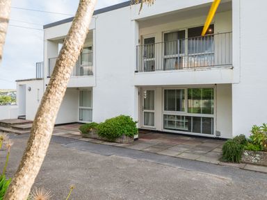 The exterior of a two story building with balconies shrubs and pavement at Westward 8 in Polzeath