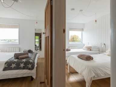 Two adjoining bedrooms each with beds towels and windows at Westward 8 Polzeath