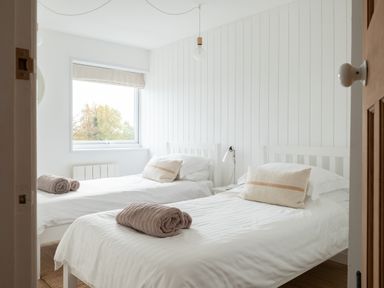 A bedroom with two single beds with white bedding and rolled towels on each bed at Westward 8 in Polzeath