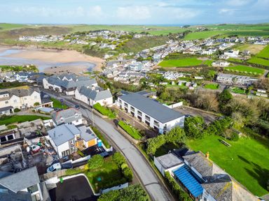 An aerial view of a coastal village with houses roads green fields and a beach at Westward 8 in Polzeath