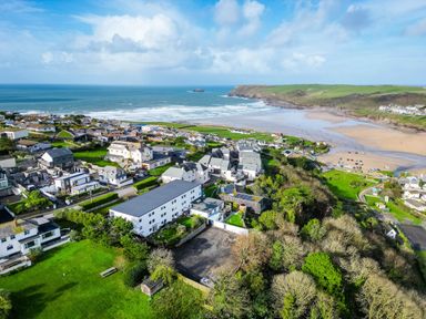 An aerial view of a coastal village with houses green fields trees and a beach at Westward 8 in Polzeath
