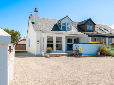 A white semi detached house with dormer windows and gravel driveway at Number 28 in Port Isaac