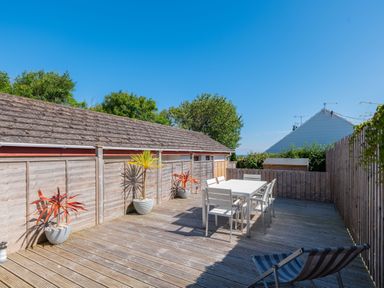 An outdoor wooden deck with a dining table and chairs and potted plants at Number 28 in Port Isaac