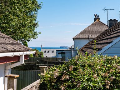 View of rooftops fences greenery and distant ocean at Number 28 in Port Isaac