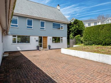 A front view of a two story house with blue siding and a paved driveway at Flaad House in Rock