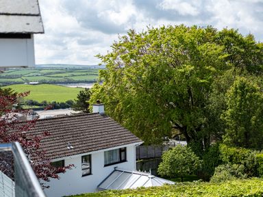 A house with a tiled roof surrounded by trees and greenery with fields and a river in the background at Flaad House in Rock